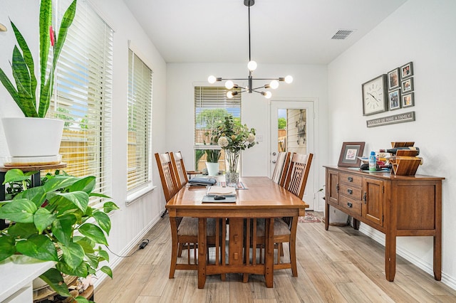 dining space featuring a chandelier, baseboards, visible vents, and light wood-style flooring