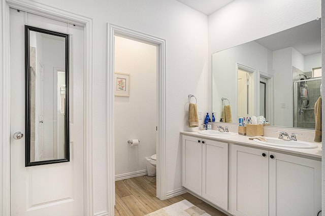 bathroom featuring double vanity, a sink, wood finished floors, and toilet