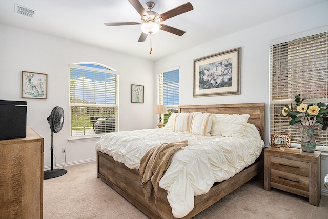 bedroom featuring baseboards, visible vents, a ceiling fan, and light colored carpet