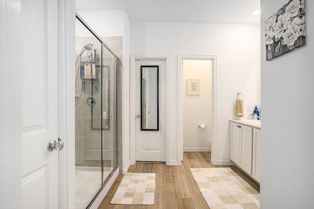 full bathroom featuring baseboards, a shower stall, wood finished floors, and vanity