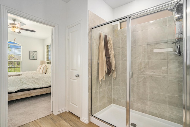 full bath featuring ceiling fan, a shower stall, wood finished floors, and connected bathroom