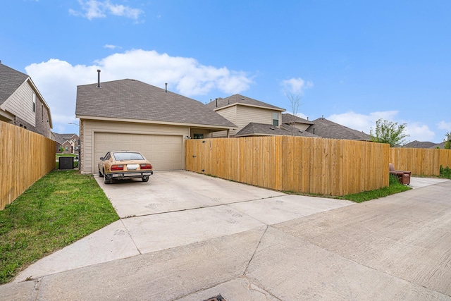 view of side of property with a yard, fence, driveway, and a garage