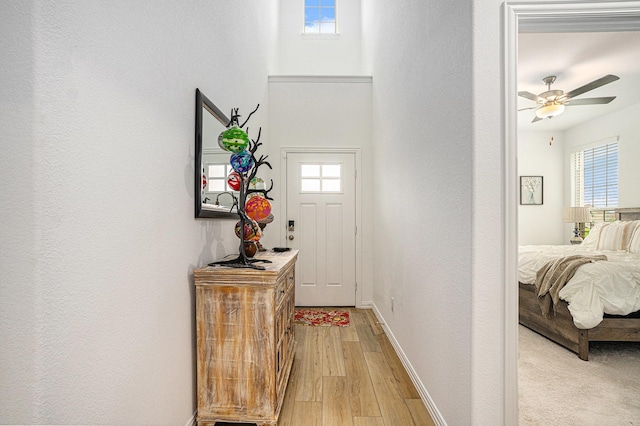 entryway with light wood-style floors, a ceiling fan, baseboards, and a textured wall