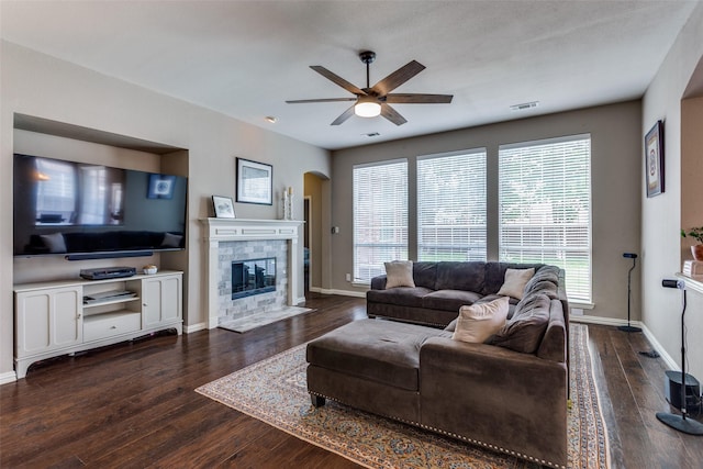 living area with visible vents, baseboards, ceiling fan, dark wood-style floors, and arched walkways