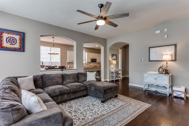 living area with arched walkways, baseboards, wood-type flooring, and ceiling fan with notable chandelier