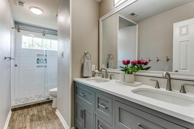 full bath featuring visible vents, a sink, wood finished floors, and a shower stall