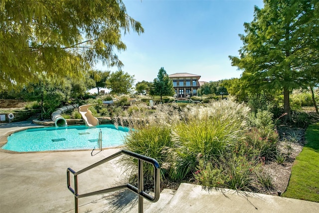community pool featuring a water slide and a patio