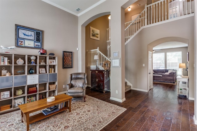sitting room with arched walkways, hardwood / wood-style flooring, baseboards, and stairs