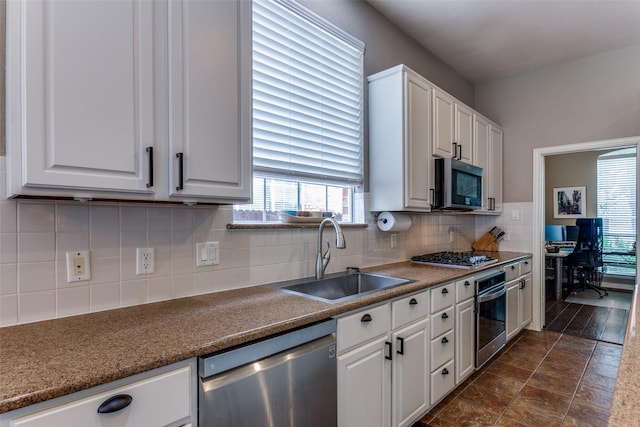 kitchen with a sink, appliances with stainless steel finishes, white cabinetry, and a healthy amount of sunlight