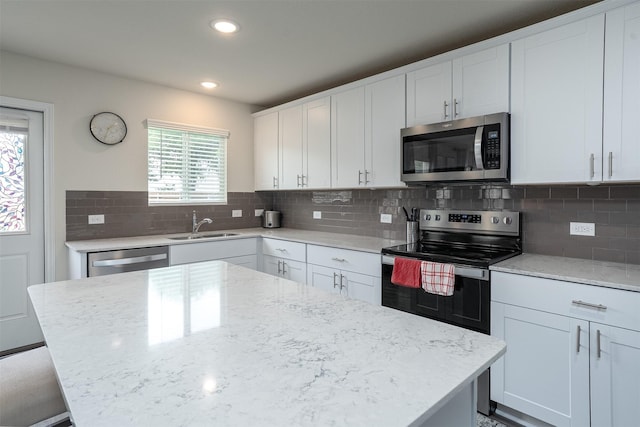 kitchen with a kitchen island, appliances with stainless steel finishes, plenty of natural light, and a sink