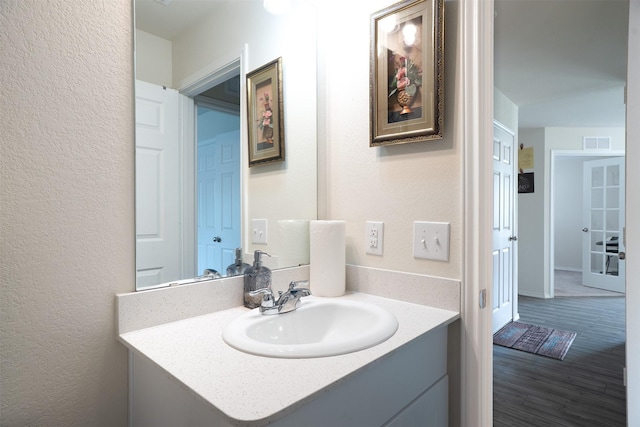 bathroom with visible vents, a textured wall, wood finished floors, and vanity