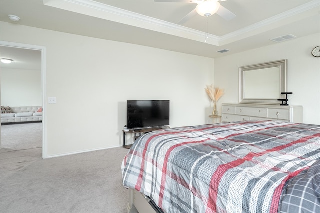 carpeted bedroom with ceiling fan, visible vents, ornamental molding, and a raised ceiling
