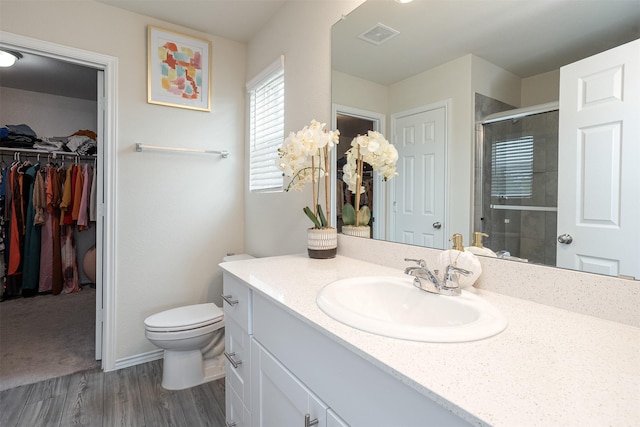 full bath featuring vanity, visible vents, toilet, a spacious closet, and a stall shower