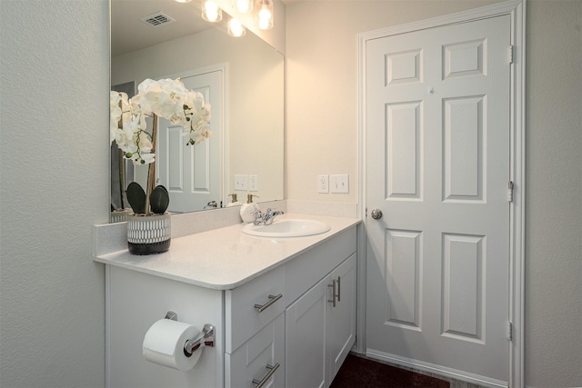 bathroom with vanity, a textured wall, and visible vents