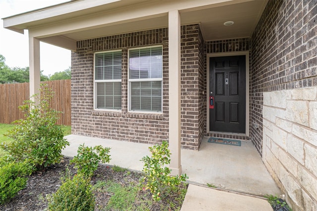 doorway to property with brick siding and fence
