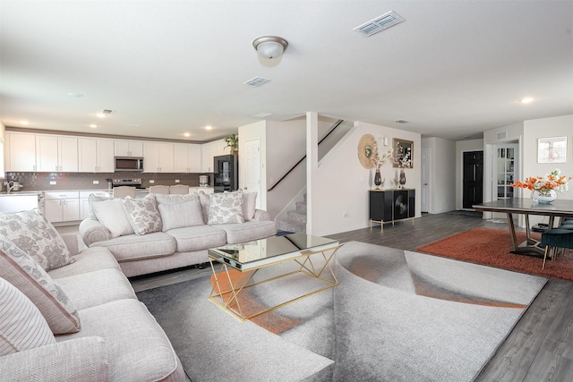 living room with visible vents, recessed lighting, stairs, and wood finished floors
