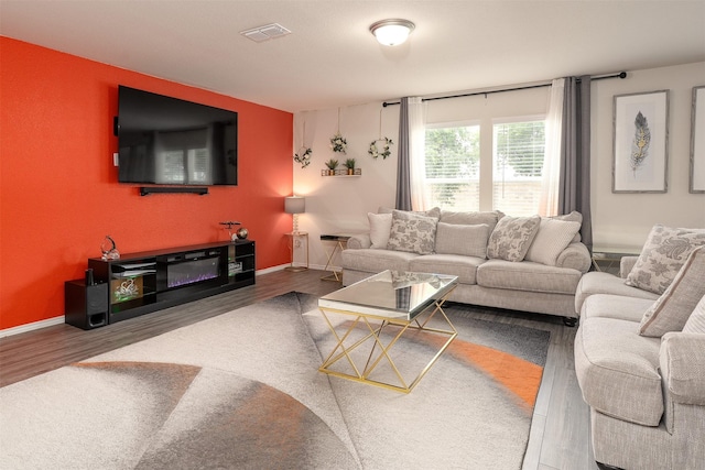 living room with baseboards, visible vents, and wood finished floors
