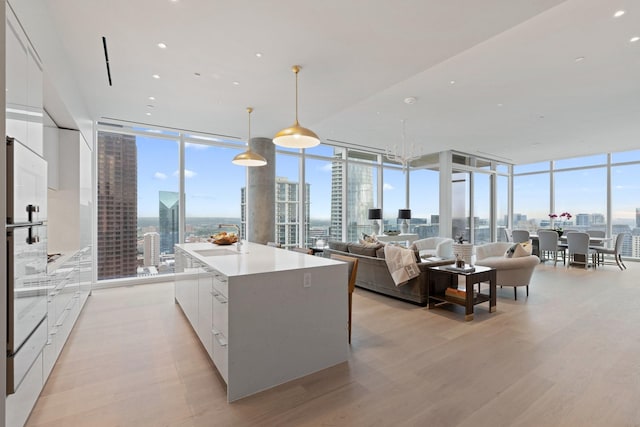 kitchen with a city view, a wall of windows, modern cabinets, and light wood finished floors