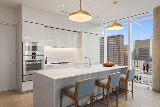 kitchen with modern cabinets, gas stovetop, white cabinets, a sink, and light wood-style flooring