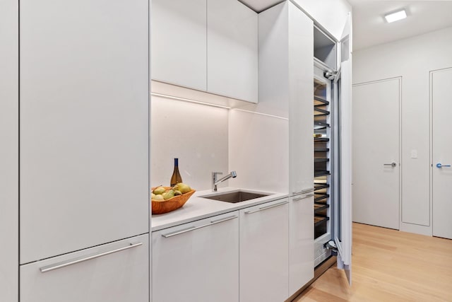 bar with a sink, white fridge, and light wood-style flooring