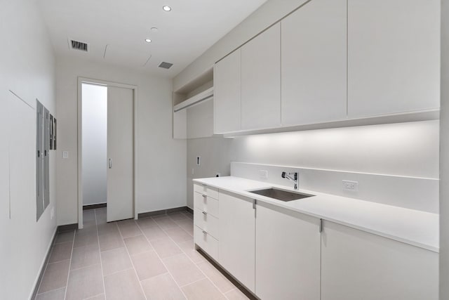 kitchen featuring a sink, light countertops, white cabinetry, baseboards, and visible vents