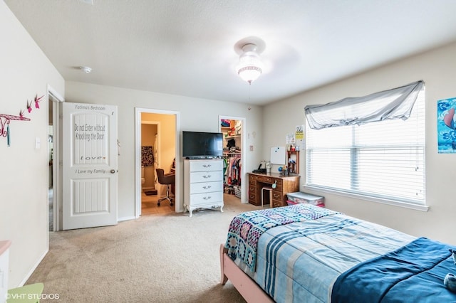 bedroom with a walk in closet, light carpet, a closet, and ensuite bath