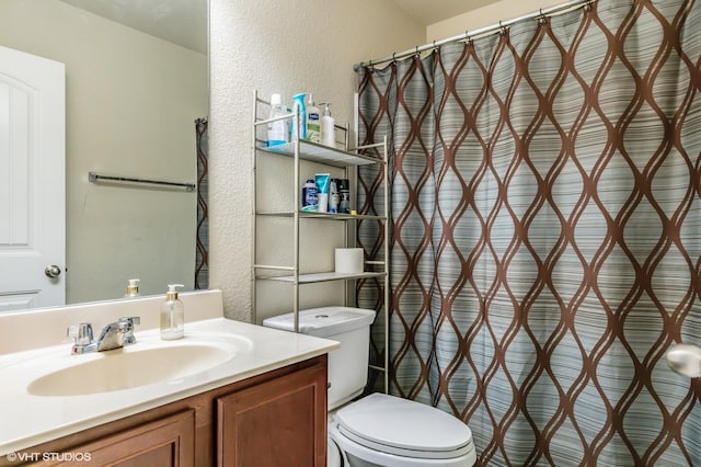 full bath with vanity, a textured wall, a shower with shower curtain, and toilet