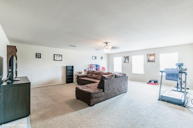 carpeted living room featuring baseboards, a ceiling fan, a textured ceiling, and visible vents