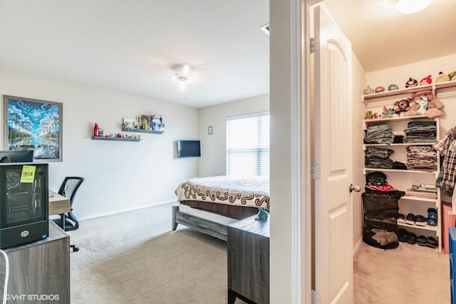 bedroom with baseboards, a ceiling fan, carpet flooring, and a walk in closet