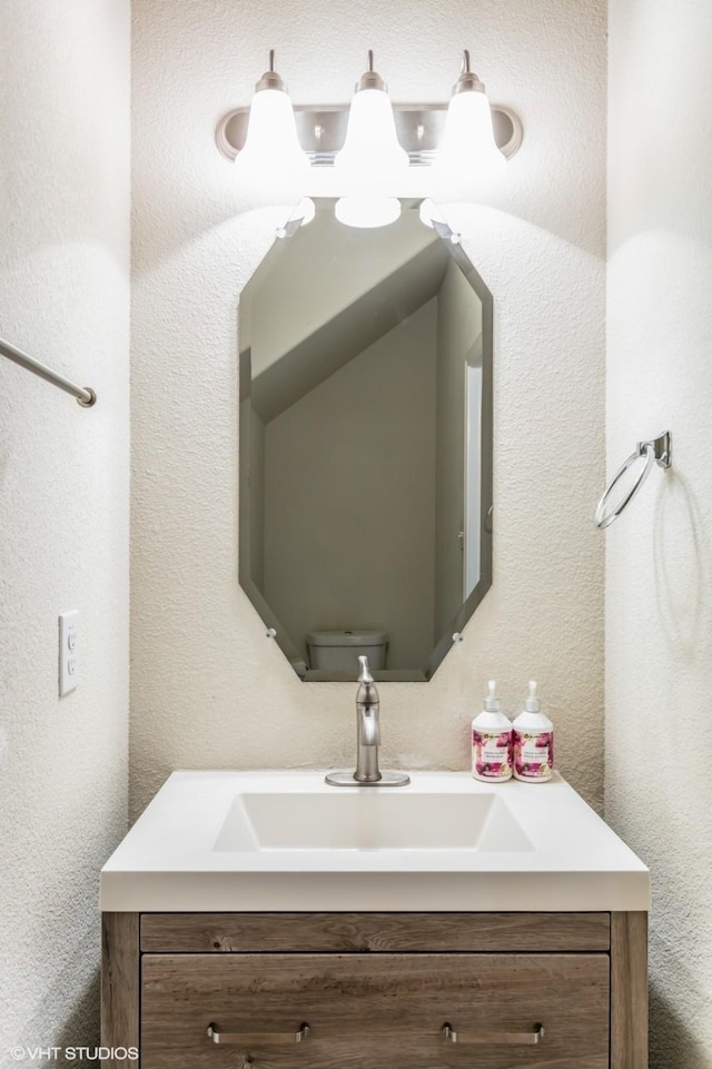 bathroom with vanity, a textured wall, and toilet