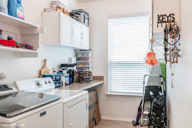 laundry room featuring light tile patterned floors, baseboards, cabinet space, and washer and clothes dryer