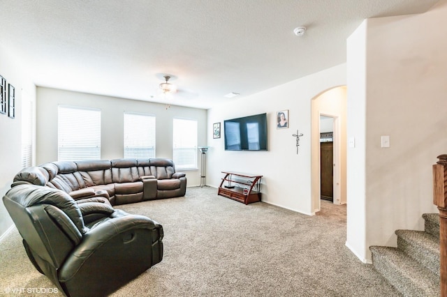 living room with carpet floors, arched walkways, a ceiling fan, and stairs