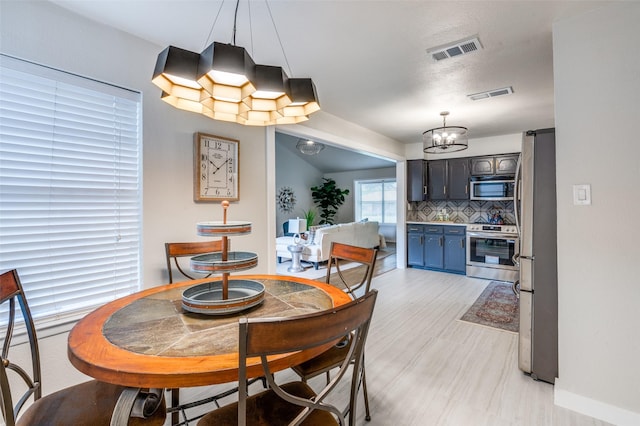 dining area featuring a chandelier, baseboards, and visible vents