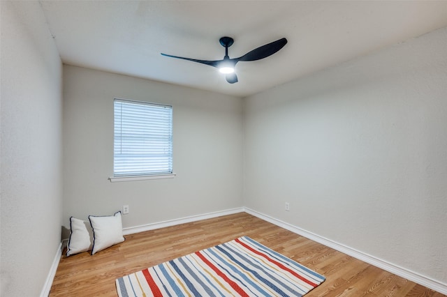 spare room featuring ceiling fan, baseboards, and light wood finished floors