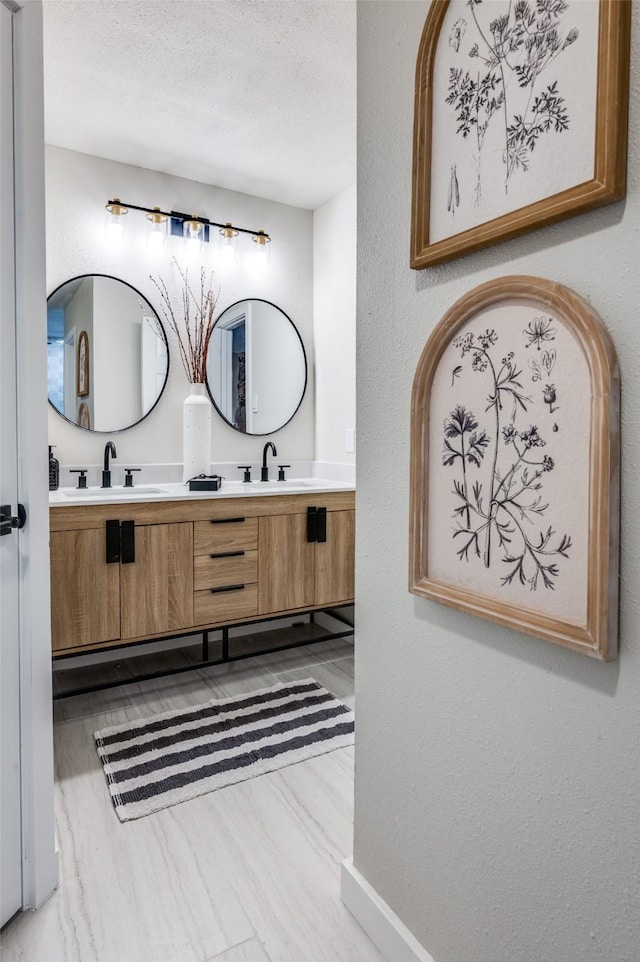 full bath with double vanity, baseboards, and a sink