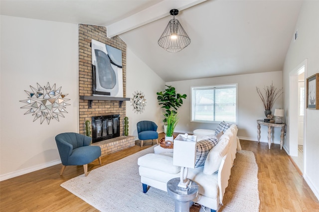 living area featuring baseboards, lofted ceiling with beams, wood finished floors, and a fireplace