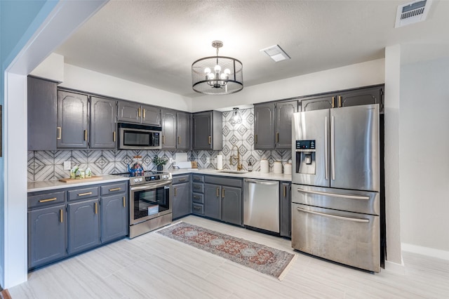 kitchen with light countertops, tasteful backsplash, stainless steel appliances, and visible vents