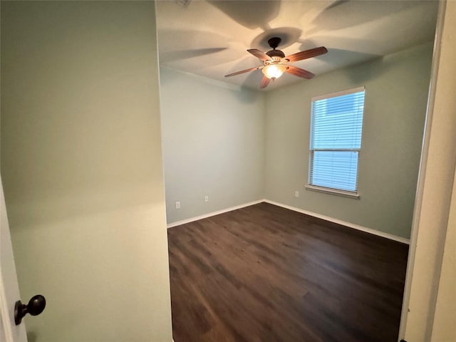 empty room with baseboards, a ceiling fan, and dark wood finished floors