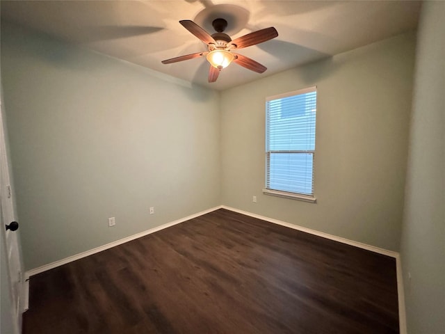 spare room featuring baseboards, ceiling fan, and dark wood-type flooring