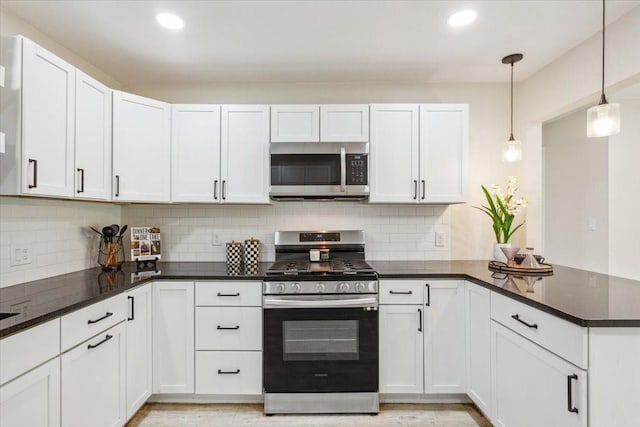 kitchen with stainless steel appliances, tasteful backsplash, white cabinetry, and a peninsula