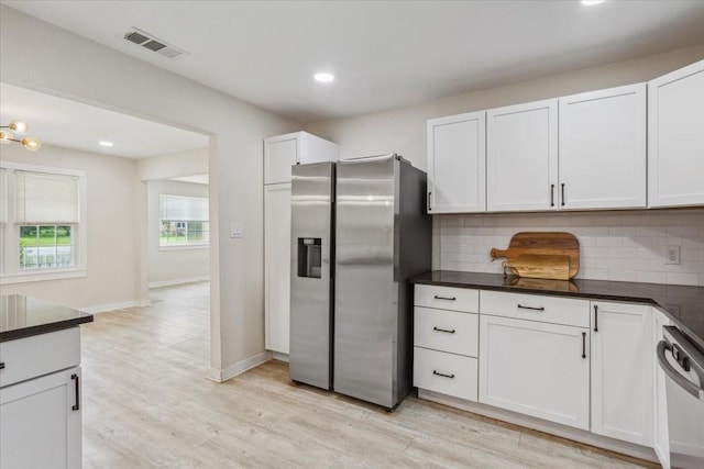 kitchen with backsplash, visible vents, dark countertops, light wood finished floors, and stainless steel appliances