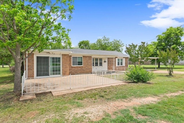 rear view of house with a lawn, fence, and brick siding