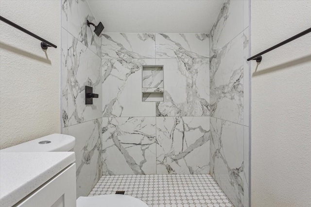 bathroom featuring vanity, toilet, a textured wall, and a stall shower