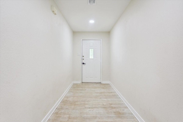 entryway with baseboards, light wood finished floors, and visible vents