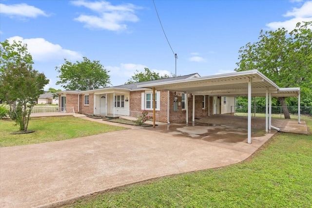 view of front of property featuring a front lawn, fence, brick siding, driveway, and a carport