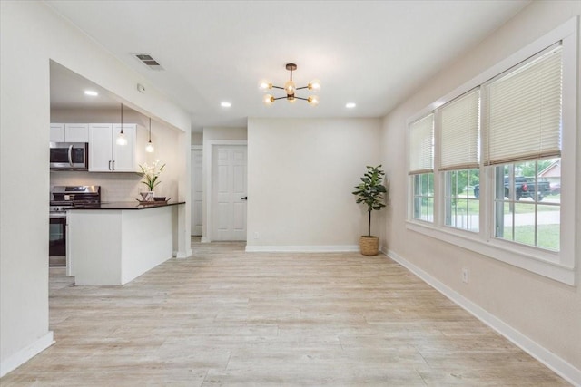 kitchen featuring white cabinets, dark countertops, appliances with stainless steel finishes, a chandelier, and recessed lighting