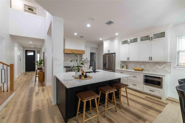 12472 Jack Pine Ct, Frisco, TX 75035 - kitchen with stainless steel appliances, decorative backsplash, light wood-style flooring, an island with sink, and recessed lighting