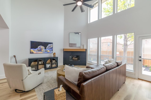 12472 Jack Pine Ct, Frisco, TX 75035 - living area featuring a high ceiling, a ceiling fan, a fireplace, and light wood-style flooring
