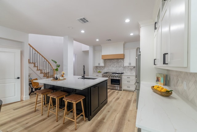 12472 Jack Pine Ct, Frisco, TX 75035 - kitchen with stainless steel appliances, a sink, light wood-style floors, decorative backsplash, and a breakfast bar area