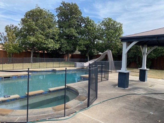 view of swimming pool featuring fence, a gazebo, a pool with connected hot tub, a water slide, and a patio